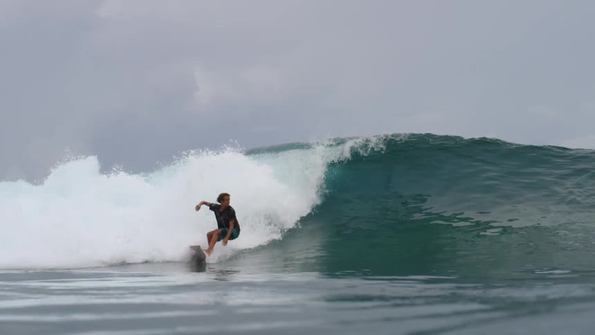 Young man riding a red and white surfboard on the ocean waves wipes out