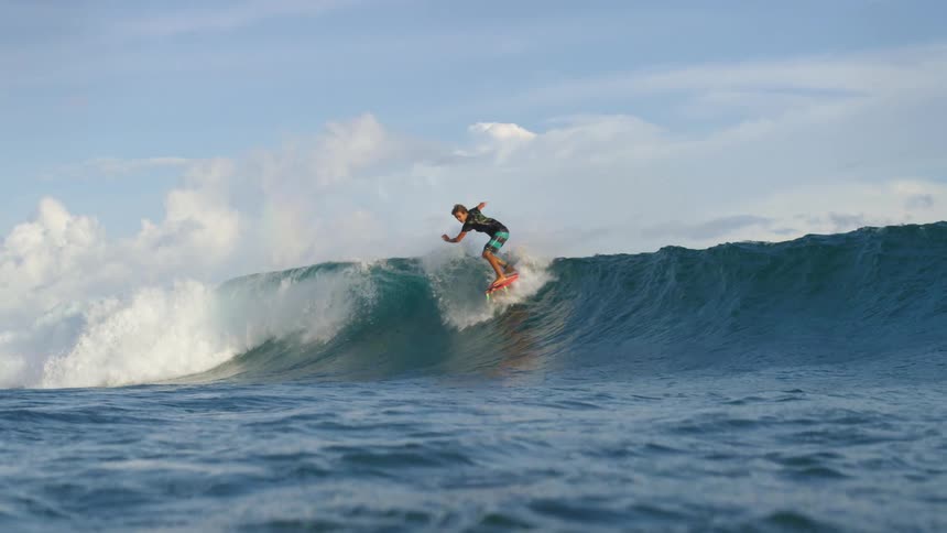 Surfer rides wave an performs jump as wave crashes
