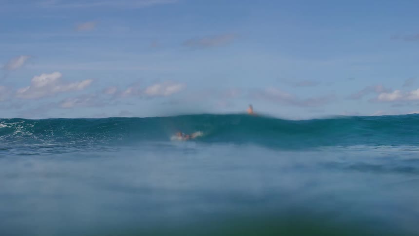 Two people are surfing on ocean waves