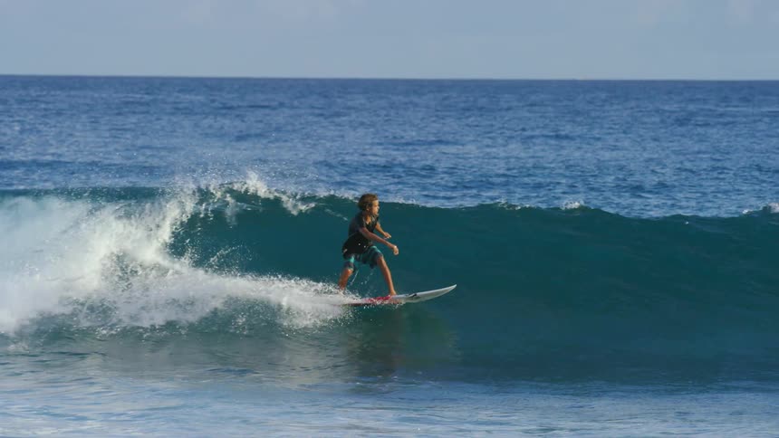A surfer goes airborne and spins in the air while surfing on the ocean during the day