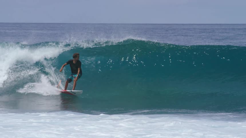 A surfer makes a sharp turn atop a wave while surfing on the ocean during the day