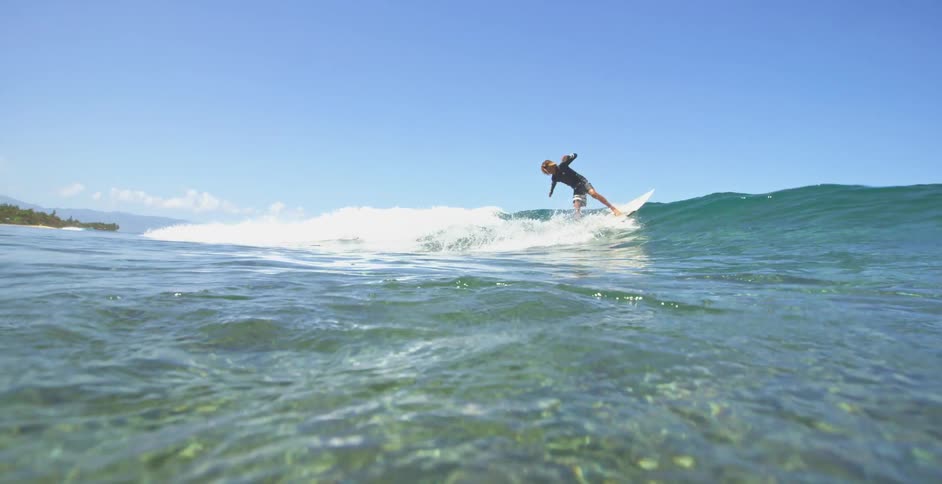 Male surfer rides on ocean wave seen from underwater