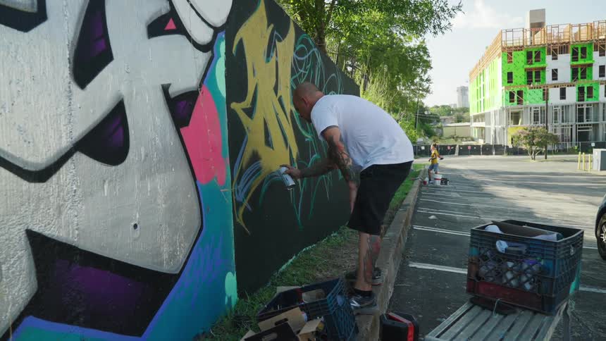 A graffiti artist is tagging a wall in an urban area
