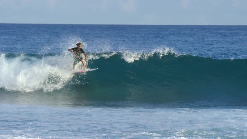 A male surfer riding an ocean wave on a sunny summer day