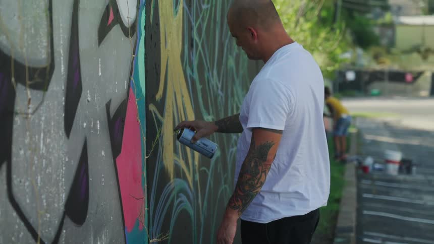A man spray painting a cement wall in a parking lot