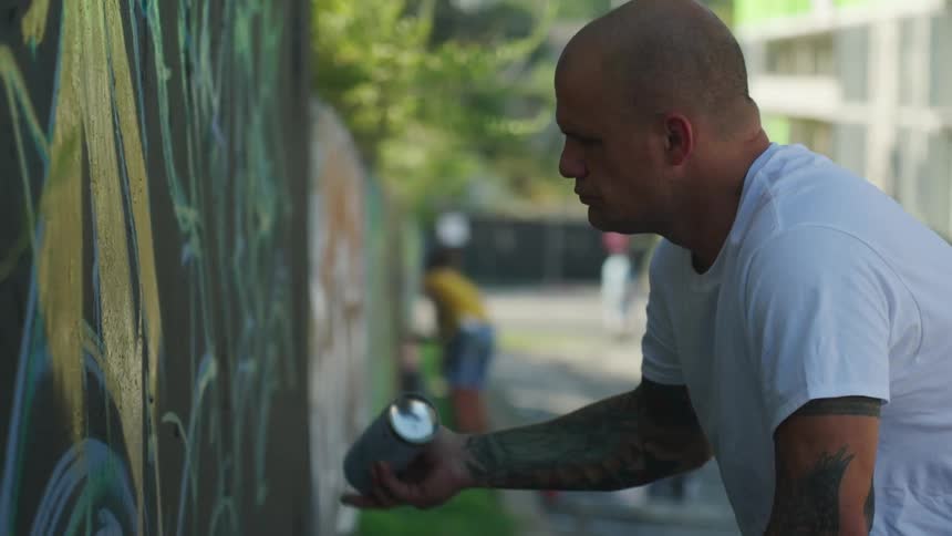 A man is spray painting a wall outdoors in spring