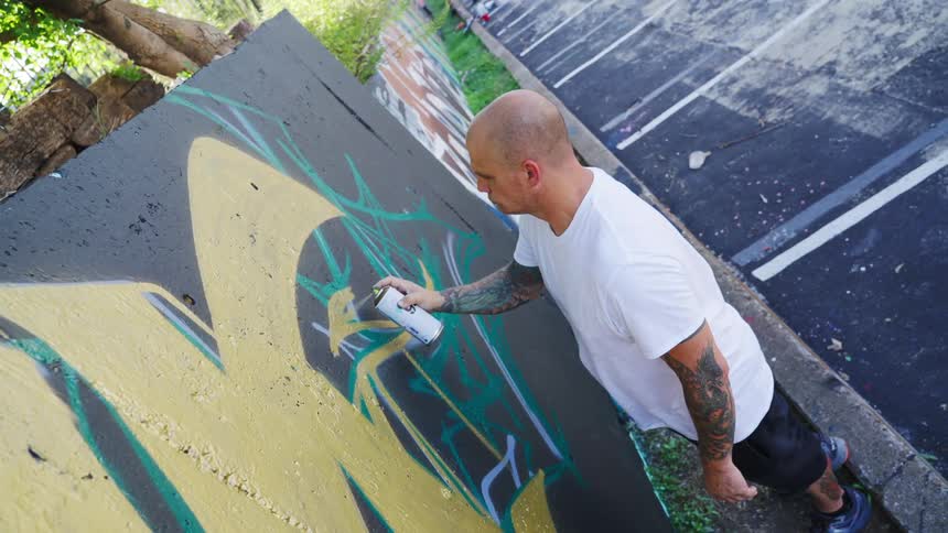 A man spray paints on a wall