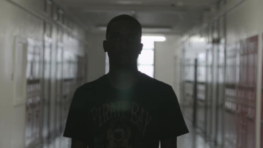 A man stands alone in a school hallway