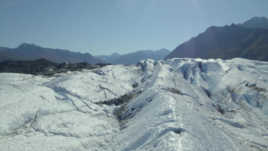 Rocky uneven terrain leads to misty mountains under clear sky