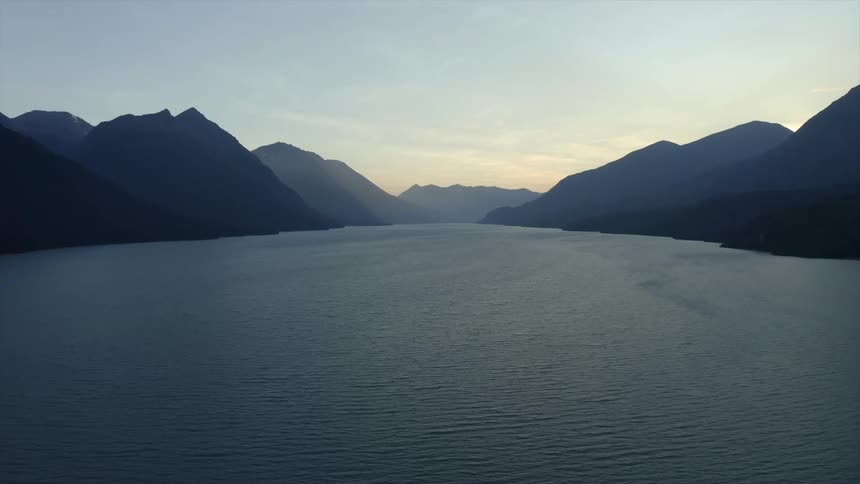 Aerial view of lake surrounded by mountains being silhouetted against the sky