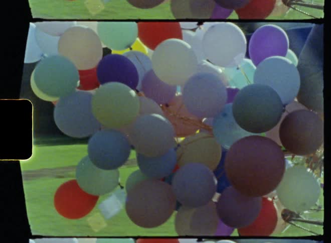 A man is riding a bike with balloons attached to it