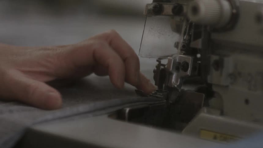 A sewing machine sews grey cloth