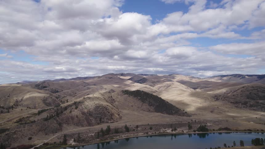 Aerial view of the barren hills under the clouds near a river