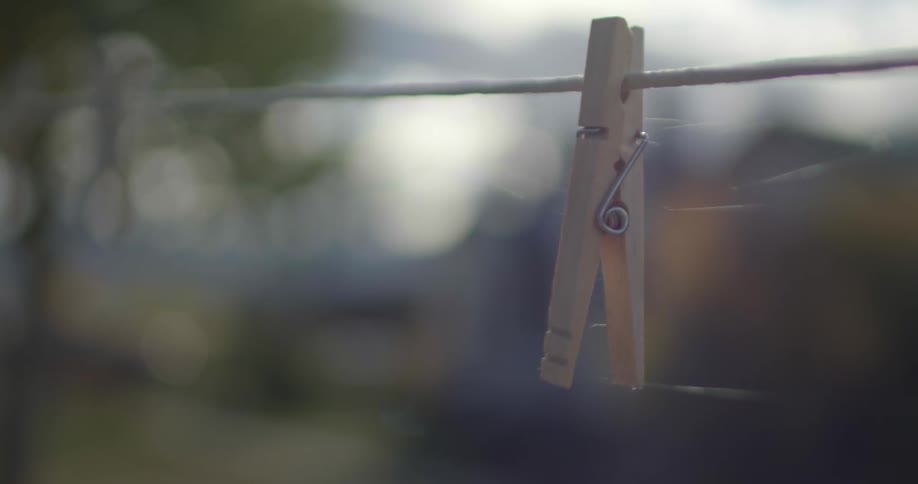 Close up of a wood pin cloth hanging from a string outdoors covered in spiderweb