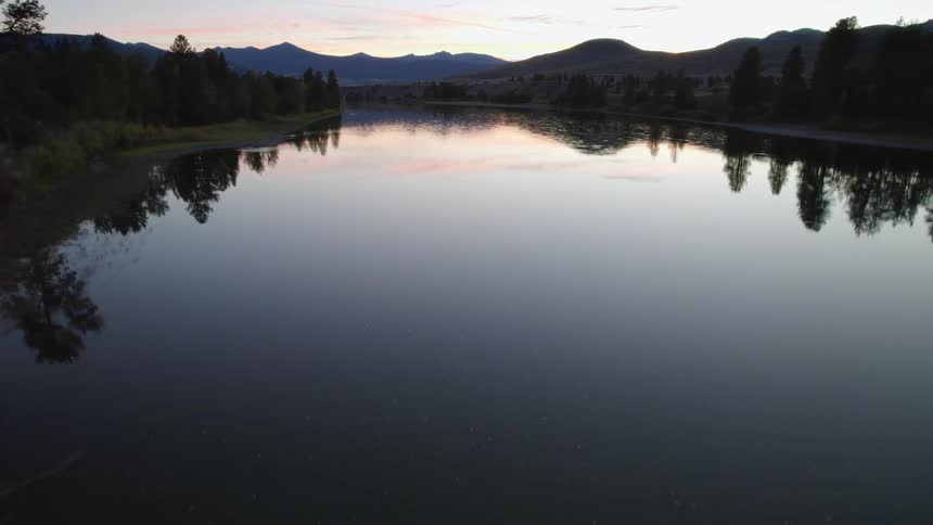 The sun is setting in the horizon of a lake in spring