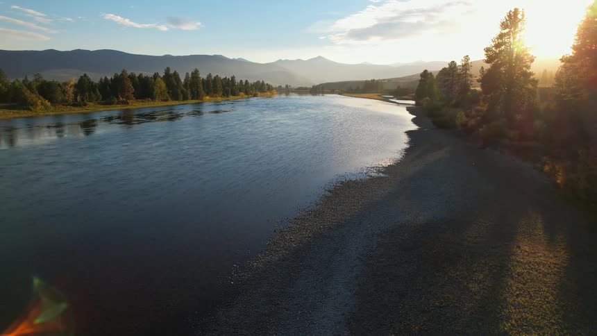 Aerial view of river bank with distant mountains at sunset