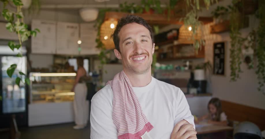 Young server standing inside a restaurant looking at the camera