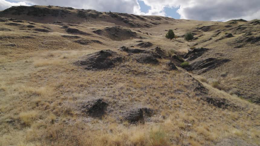 Scrub covered slopes surround ravine under cloudy sky