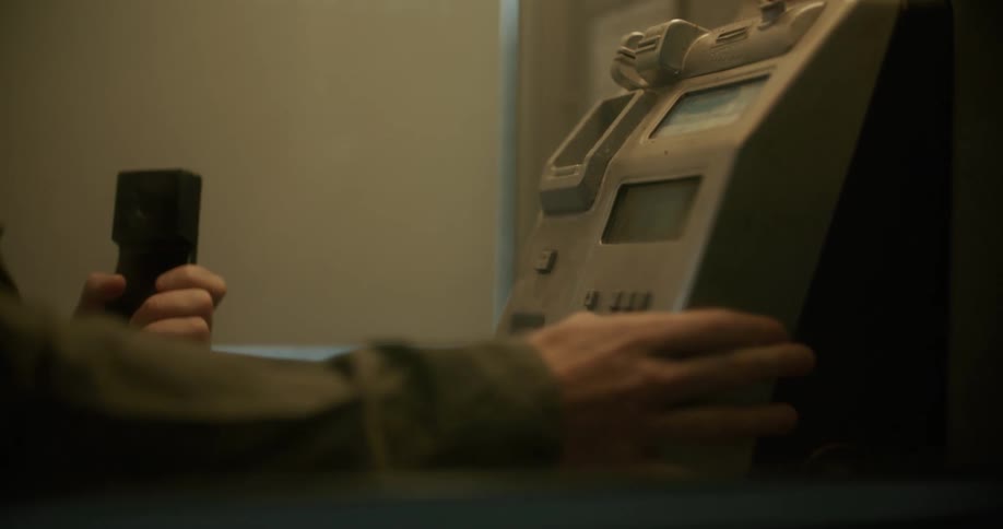 Man picks up the handset of a public payphone to make a call