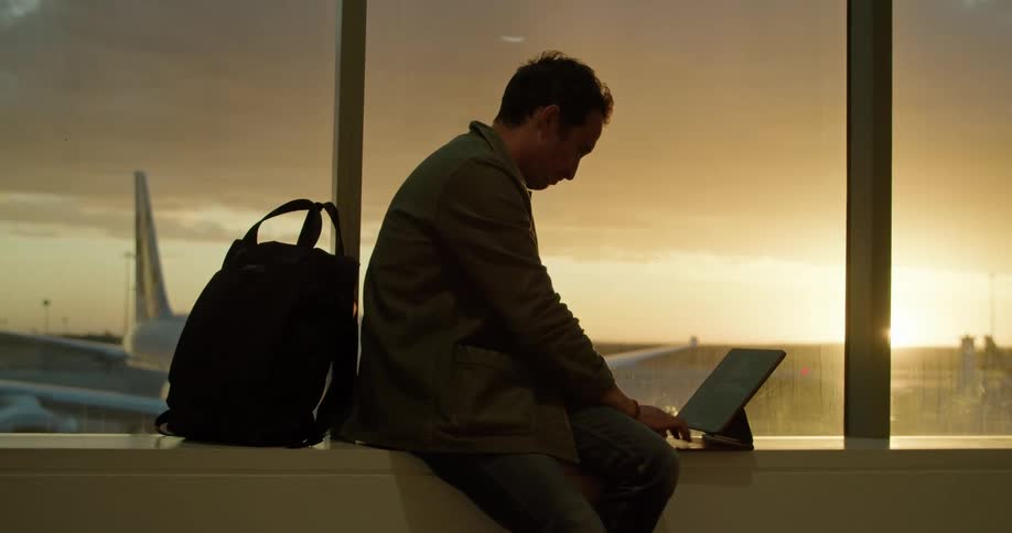 A man sitting next to a window using a computer