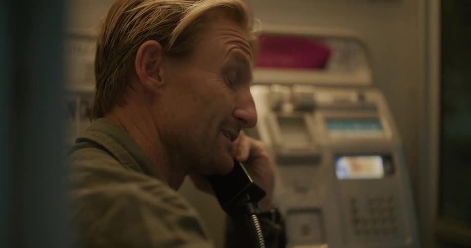 A man is standing inside talking on a telephone