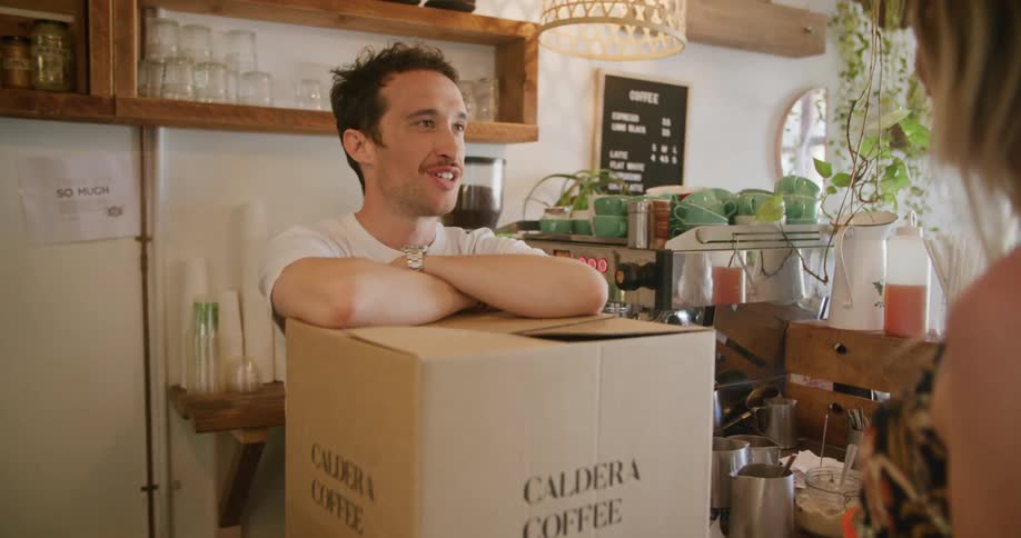 A woman puts a box on the counter while talking to a man