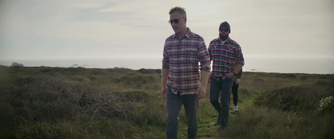 Men walk along path through grassy field
