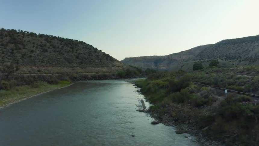 Cars are driving near a river at dusk