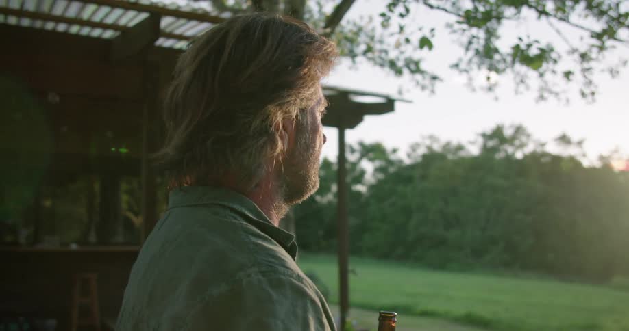 A man is standing outdoors and drinking a beer