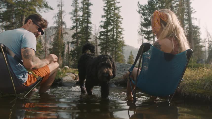 Man and woman are outdoors camping with their dog