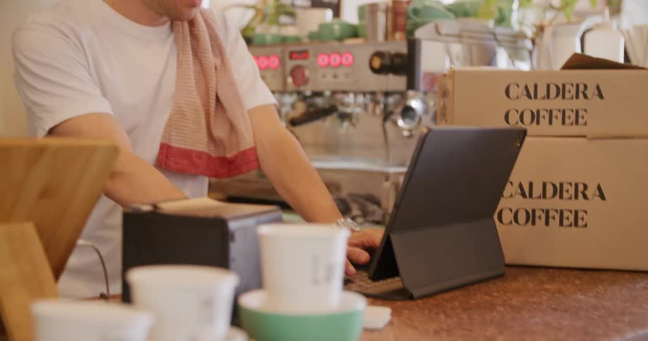 A man is typing on his tablet in the cafe