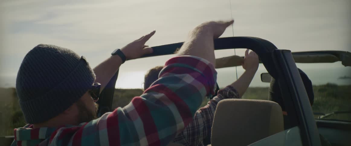Three men ride in a car on a cloudy day
