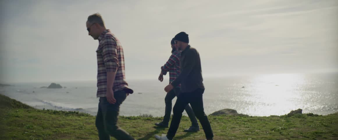 Male friends walking along trail overlooking the coast