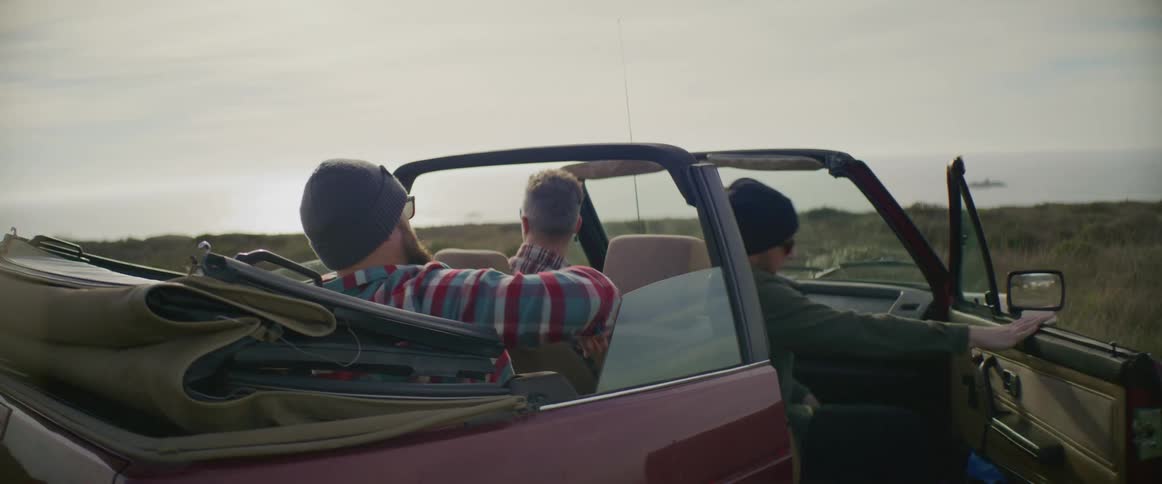 Three men are getting into a parked car