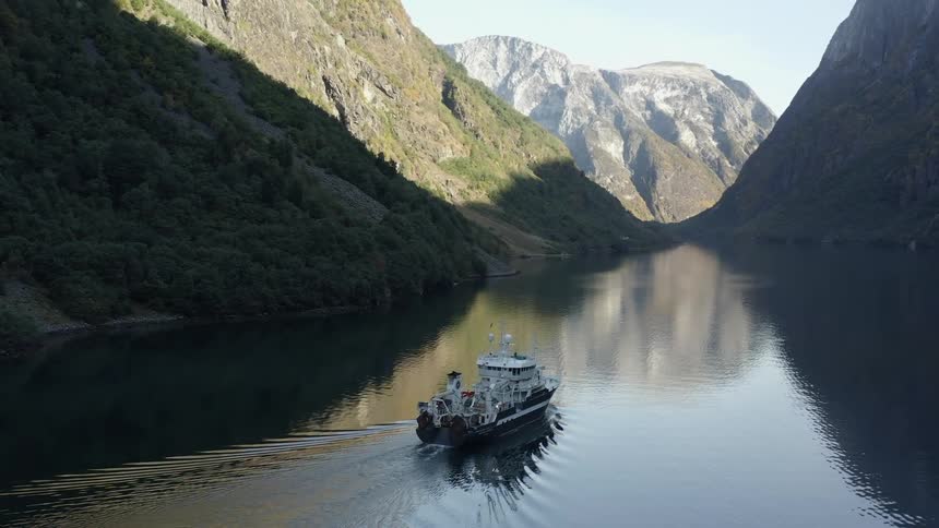 A boat is on the river surrounded by mountains