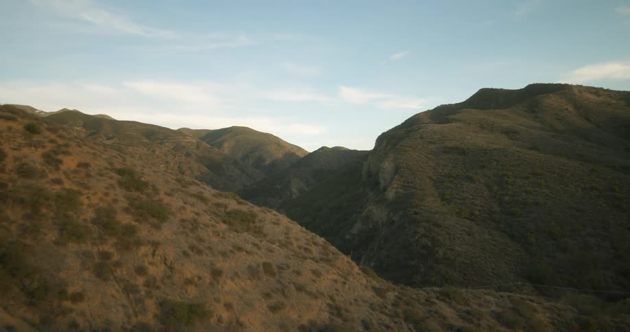 Mountains with plants growing on them and a few clouds in the sky