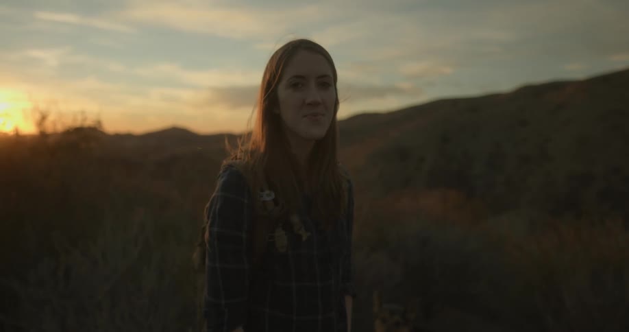 A woman is standing outdoors at dusk in spring