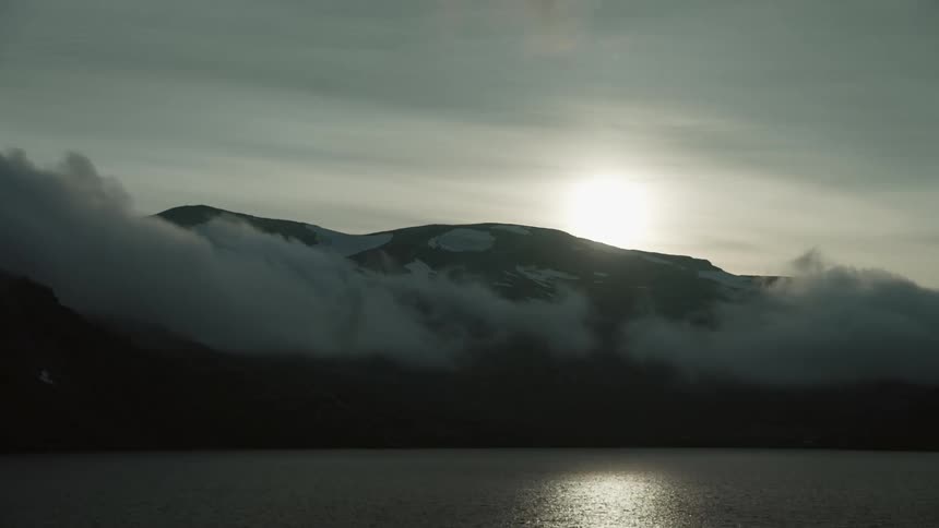 Clouds rolling over the hilly shore as the sun sets