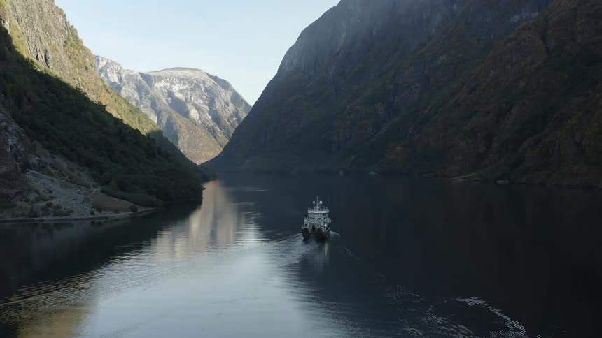 A boat sails down a river in a valley