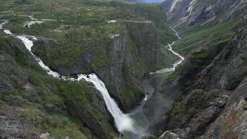 An aerial view of a waterfall crashing down a canyon in to the river below