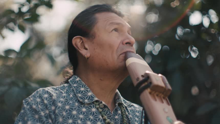 Man plays woodwind while stand outdoors on sunny day