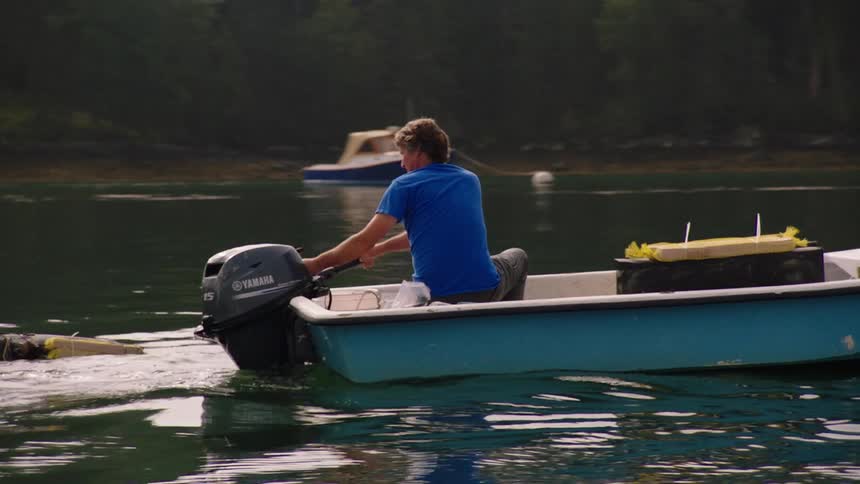 A man is pulling nets onto his boat