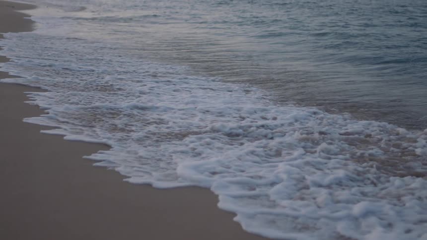 Waves crash onto beach creating foam