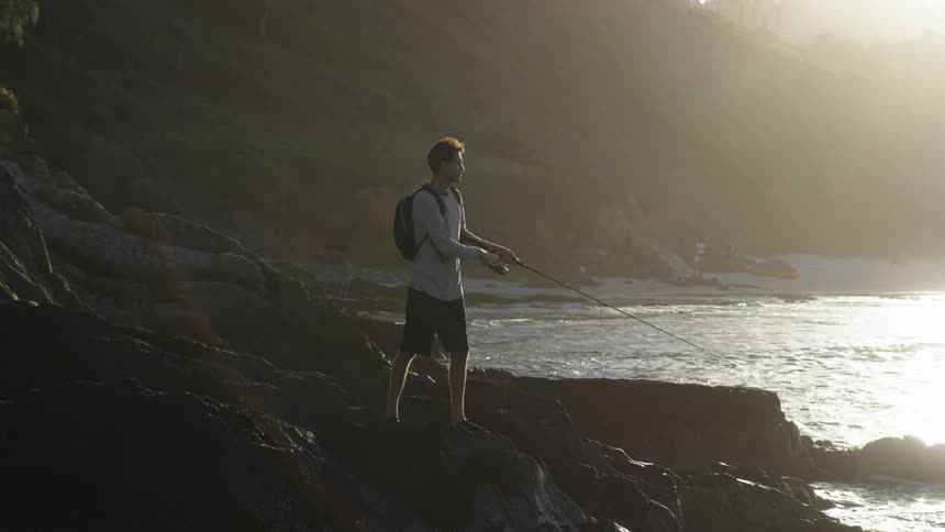 Man fishing off the rocks on the coast in the morning hours