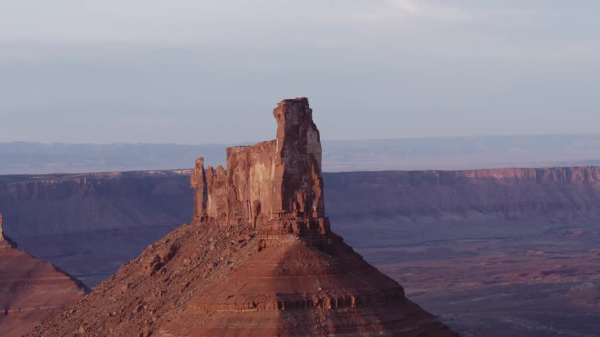 A rock formation sits on top of a canyon overlooking a wide valley