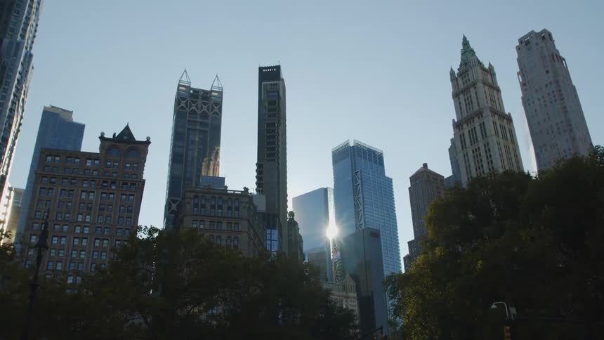 The sun is peaking through the tall buildings in the city