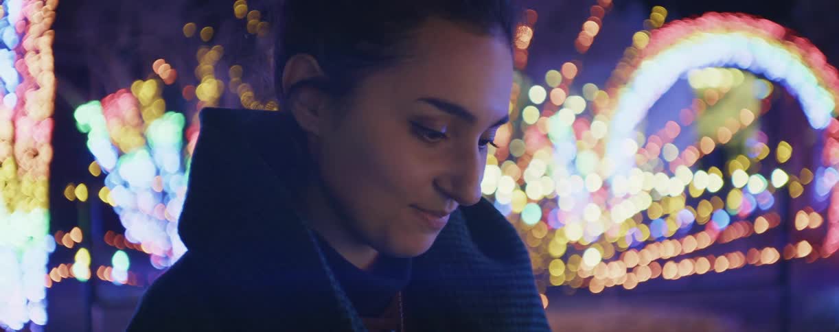 A woman is smiling as she looks down near a lighted display