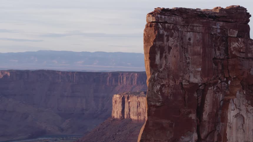 Tall rock formations with mountains on the horizon under a hazy sky