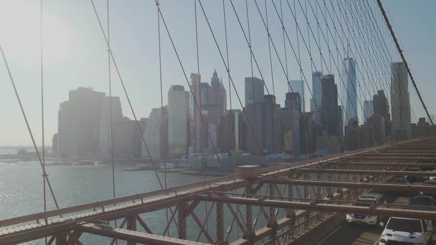 Cars driving across a bridge with a city skyline in the distance