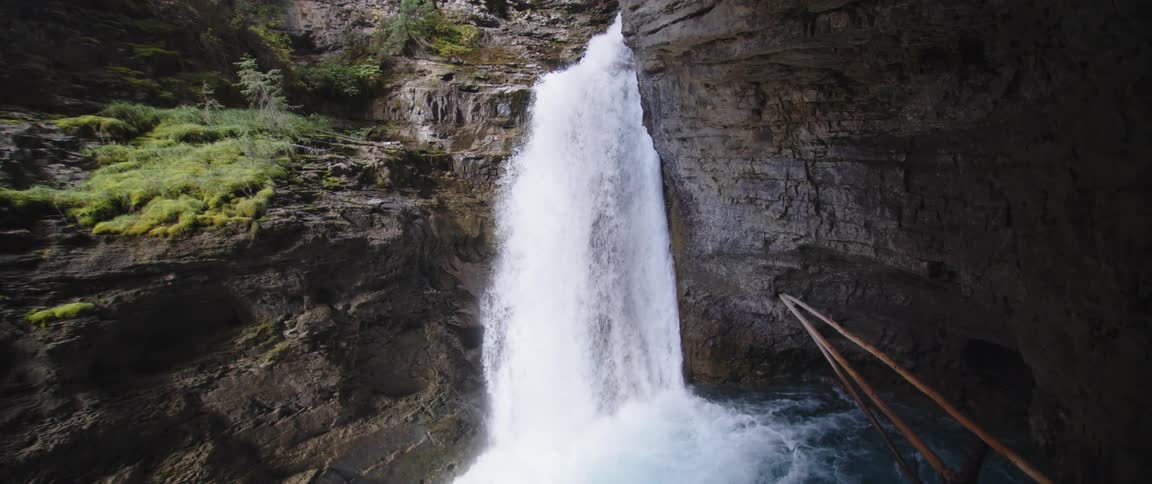 Waterfalls flowing down the side of a cliff into a stream below